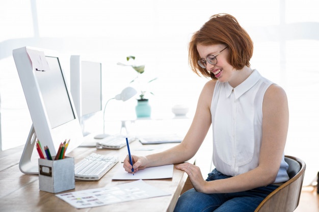 smiling-hipster-business-woman-sketching-paper-her-desk_107420-11255
