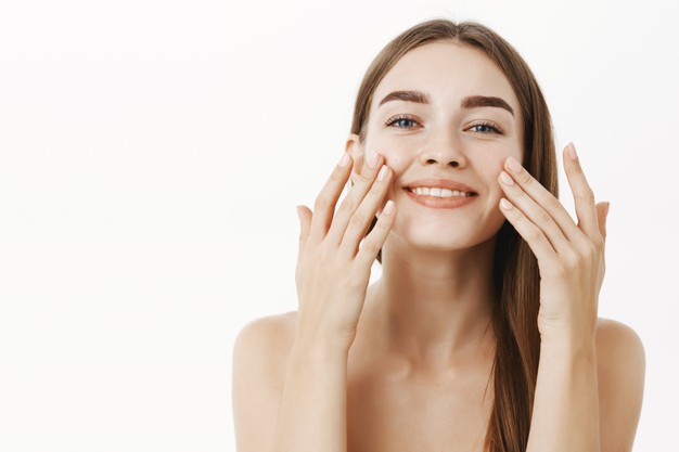charming-relaxed-gentle-young-woman-making-cosmetological-procedure-applying-facial-cream-face-with-fingers-smiling-broadly-feeling-perfect-taking-care-skin_176420-24010