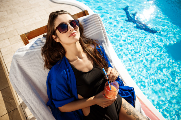 beautiful-woman-drinking-cocktail-lying-chaise-near-swimming-pool_176420-1578