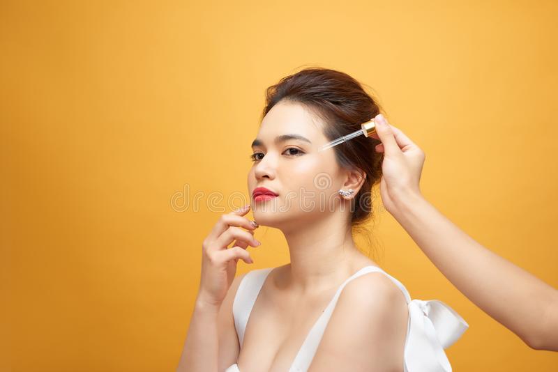 close-up-adult-woman-beauty-portrait-one-hand-applying-serum-her-face-yellow-background-close-up-adult-woman-beauty-portrait-157789422